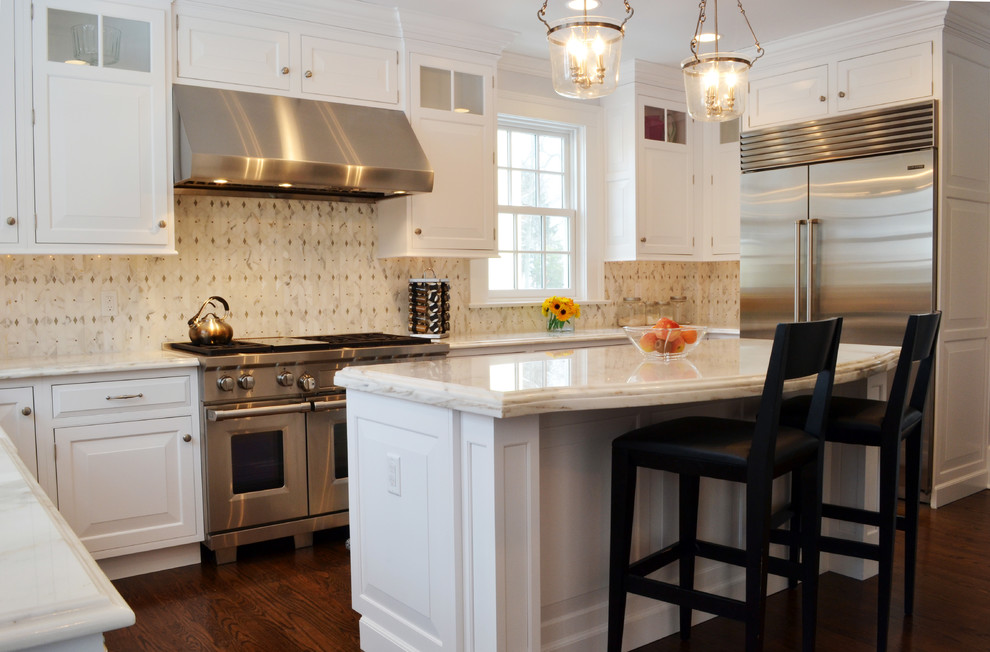 Mid-sized transitional u-shaped medium tone wood floor enclosed kitchen photo in New York with a farmhouse sink, beaded inset cabinets, white cabinets, marble countertops, multicolored backsplash, mosaic tile backsplash, stainless steel appliances and an island
