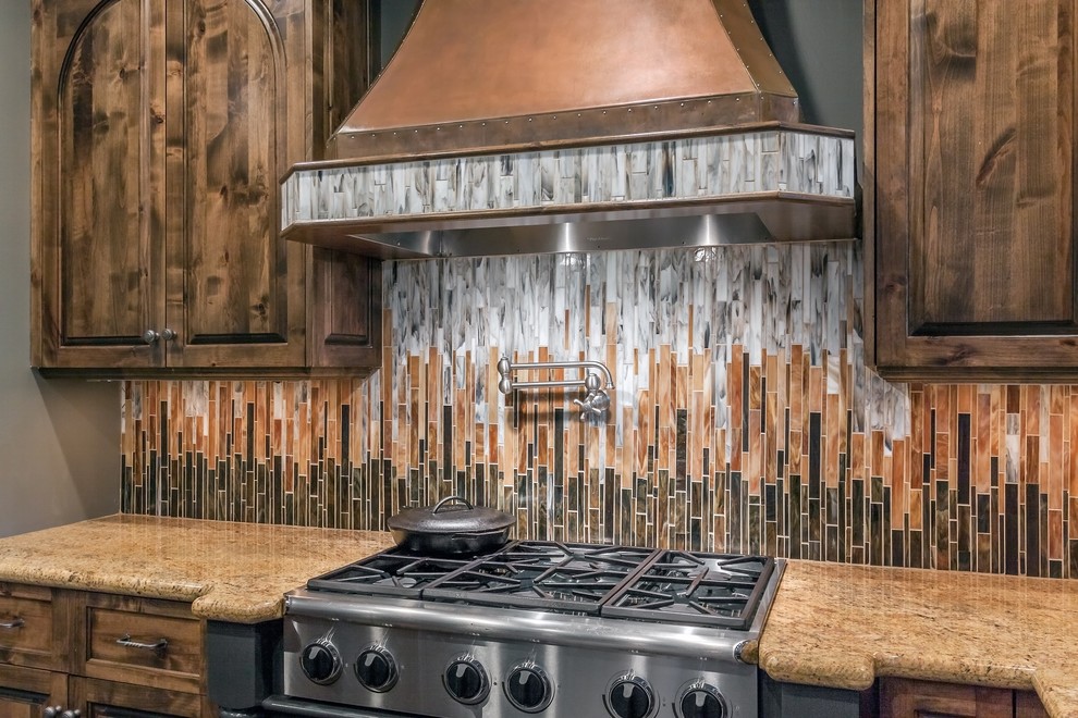 Klassisk inredning av ett mycket stort kök, med en rustik diskho, skåp i mellenmörkt trä, granitbänkskiva, flerfärgad stänkskydd, stänkskydd i glaskakel, rostfria vitvaror, mörkt trägolv och en köksö