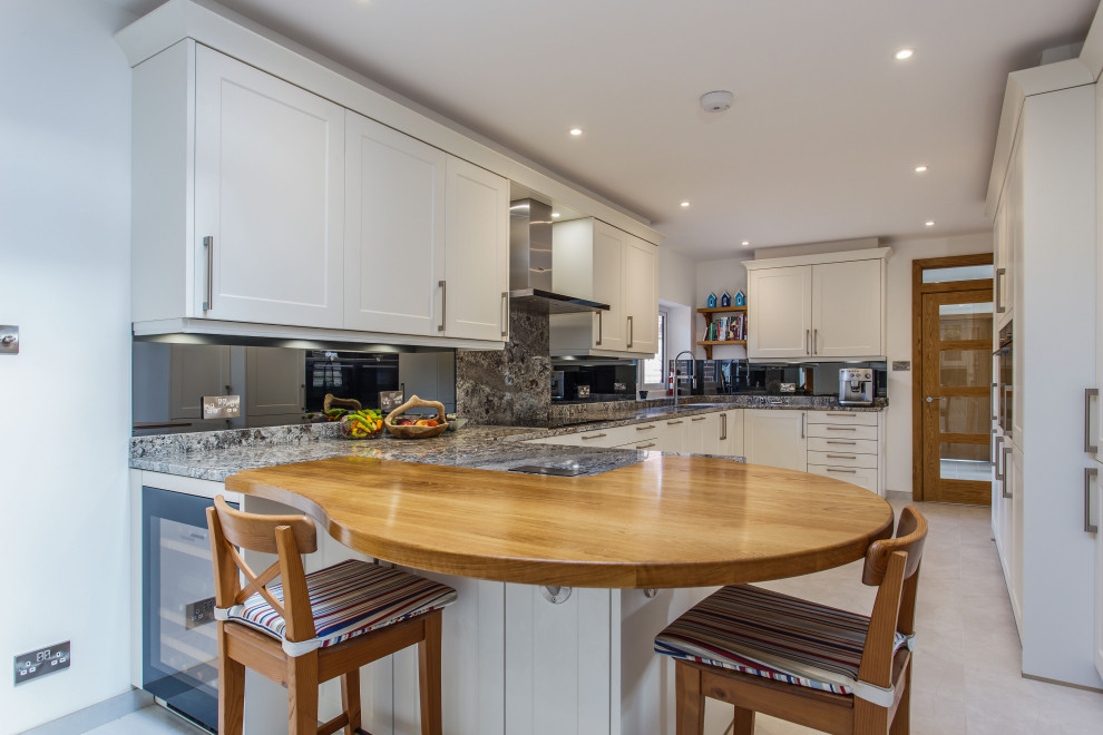 Moderne Wohnküche mit Schrankfronten im Shaker-Stil, weißen Schränken, Granit-Arbeitsplatte und Rückwand aus Spiegelfliesen in Sussex
