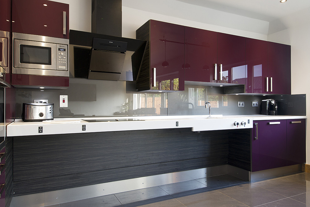 Medium sized contemporary l-shaped open plan kitchen in Essex with an integrated sink, flat-panel cabinets, purple cabinets, concrete worktops, metallic splashback, glass sheet splashback, stainless steel appliances, porcelain flooring and grey floors.