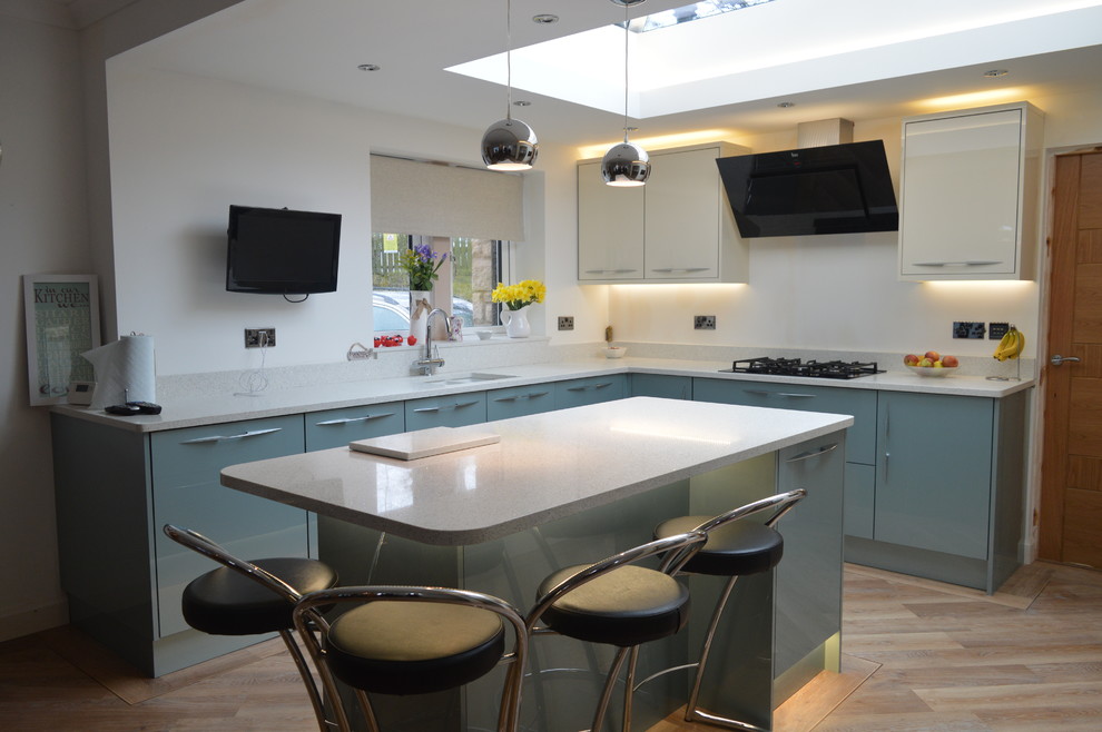 Example of a large trendy l-shaped vinyl floor eat-in kitchen design in Other with flat-panel cabinets, blue cabinets, quartzite countertops, black appliances and an island