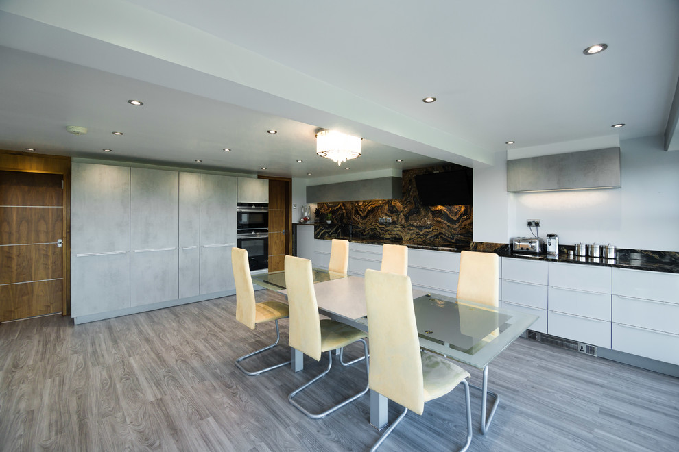 Photo of a modern l-shaped open plan kitchen in Other with a built-in sink, glass-front cabinets, stainless steel cabinets, granite worktops, multi-coloured splashback, stone slab splashback, stainless steel appliances, vinyl flooring, grey floors and multicoloured worktops.