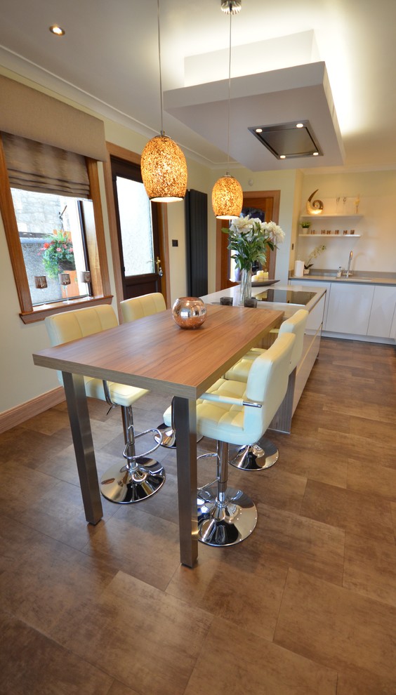 Photo of a medium sized contemporary u-shaped kitchen/diner in Glasgow with laminate countertops, mirror splashback, an island, a double-bowl sink, flat-panel cabinets, white cabinets, white splashback, white appliances, medium hardwood flooring and brown floors.