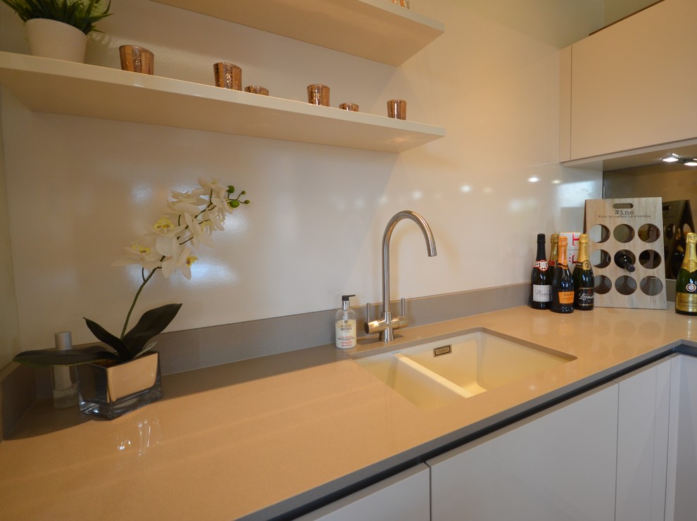 Idéer för ett mellanstort modernt kök, med laminatbänkskiva, spegel som stänkskydd, en köksö, en dubbel diskho, släta luckor, vita skåp, vitt stänkskydd, vita vitvaror, mellanmörkt trägolv och brunt golv