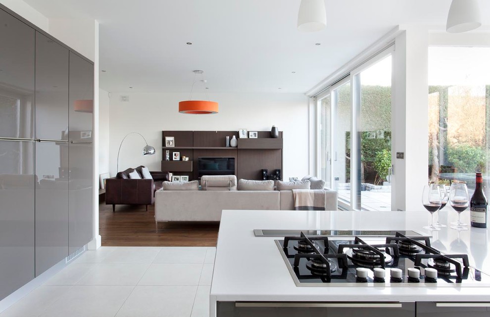 Design ideas for an expansive contemporary open plan kitchen in Dublin with an integrated sink, flat-panel cabinets, white cabinets, engineered stone countertops, white splashback, glass sheet splashback, stainless steel appliances, porcelain flooring and an island.