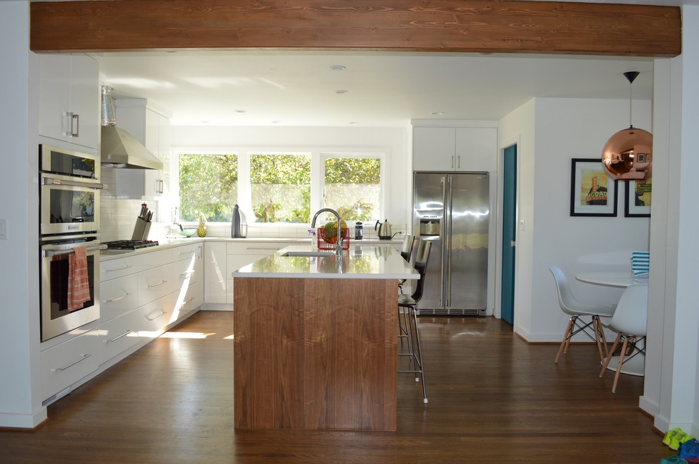 Cette image montre une grande cuisine américaine design en L avec un placard à porte plane, des portes de placard blanches et îlot.