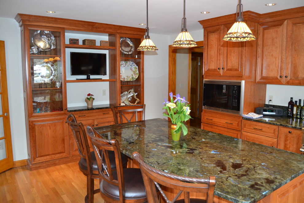 Example of a mid-sized classic l-shaped medium tone wood floor eat-in kitchen design in Boston with an undermount sink, raised-panel cabinets, medium tone wood cabinets, granite countertops, green backsplash, stone tile backsplash, stainless steel appliances and an island