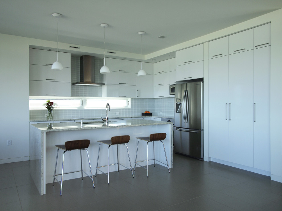 Exempel på ett modernt kök, med rostfria vitvaror, granitbänkskiva, släta luckor, vita skåp, en undermonterad diskho och stänkskydd i glaskakel