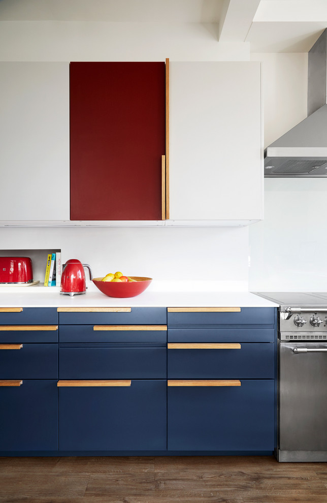 Foto de cocina contemporánea con armarios con paneles lisos, puertas de armario azules, electrodomésticos de acero inoxidable, suelo de madera en tonos medios, suelo marrón y encimeras blancas