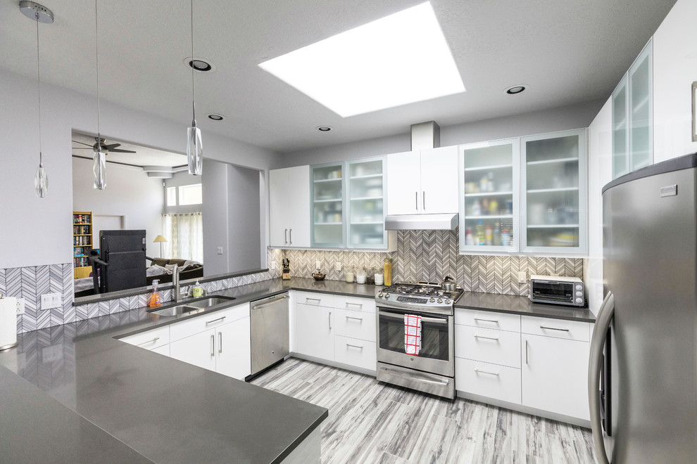 Inspiration for a large modern u-shaped porcelain tile and gray floor open concept kitchen remodel in Albuquerque with an undermount sink, flat-panel cabinets, white cabinets, quartz countertops, gray backsplash, glass tile backsplash, stainless steel appliances, no island and gray countertops