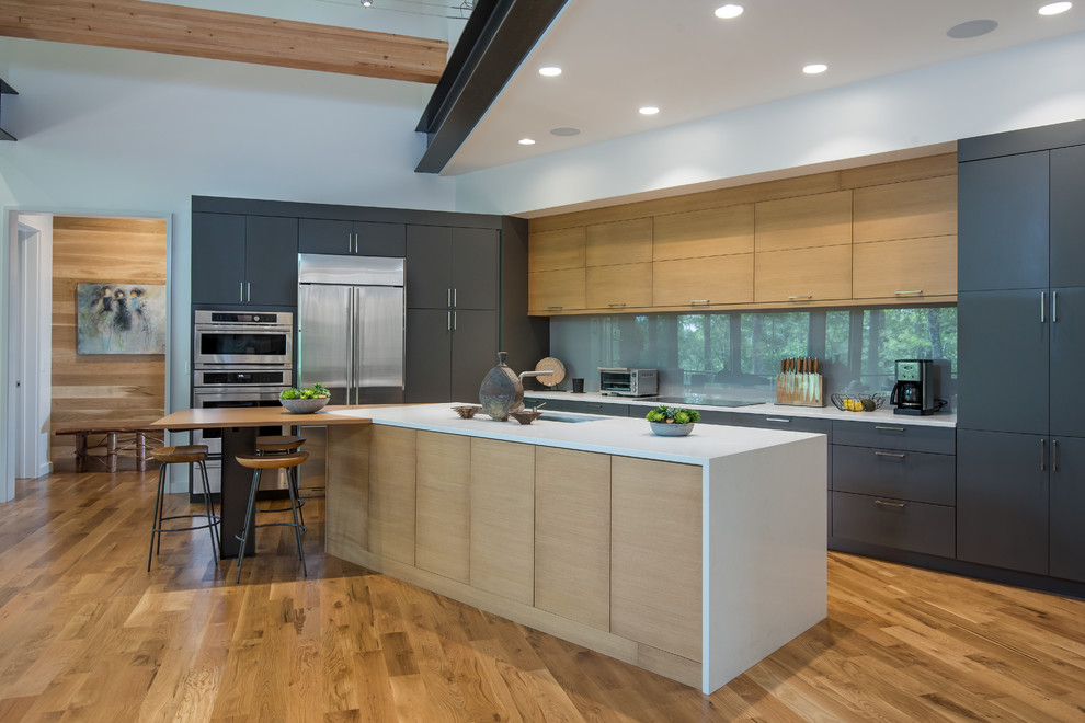 Design ideas for a contemporary galley kitchen/diner in Other with flat-panel cabinets, grey cabinets, grey splashback, stainless steel appliances, medium hardwood flooring, an island and brown floors.