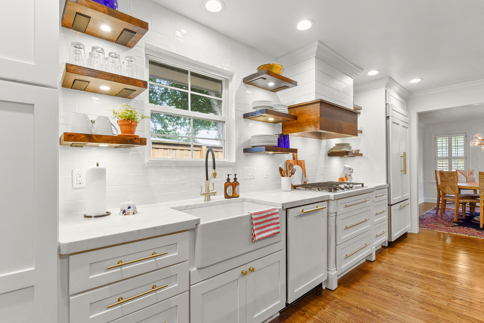 Bild på ett mellanstort funkis vit vitt kök, med en rustik diskho, skåp i shakerstil, vita skåp, bänkskiva i kvarts, vitt stänkskydd, stänkskydd i tunnelbanekakel, rostfria vitvaror, mellanmörkt trägolv, en köksö och brunt golv