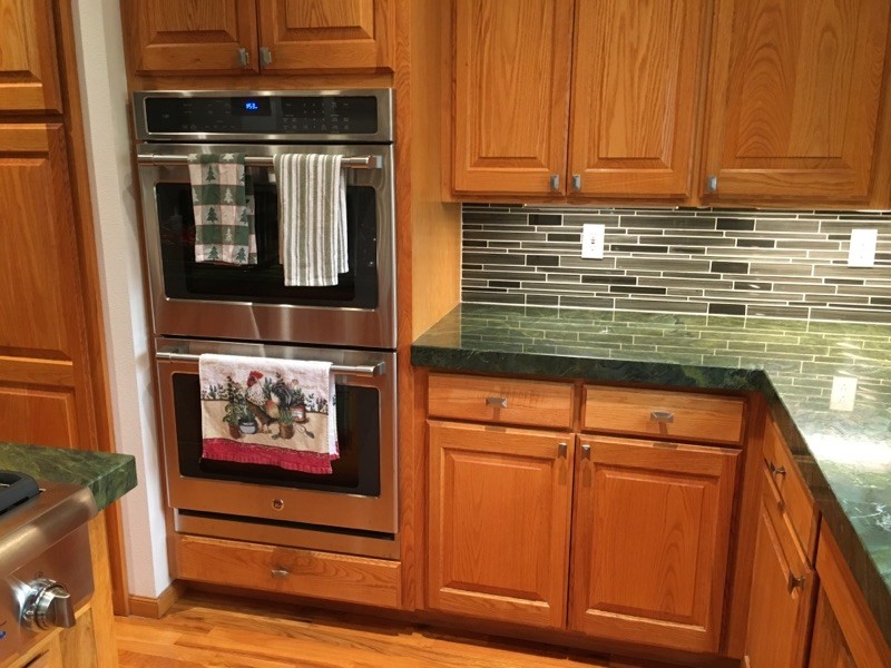 Exemple d'une cuisine en bois brun avec un évier encastré, un plan de travail en granite, une crédence multicolore, une crédence en carreau de verre, un électroménager en acier inoxydable, îlot et un plan de travail vert.