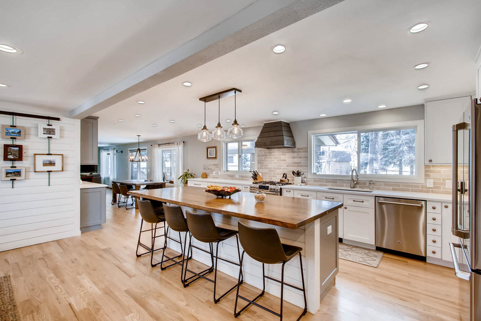Eat-in kitchen - large transitional l-shaped light wood floor and yellow floor eat-in kitchen idea in Other with an undermount sink, shaker cabinets, white cabinets, quartz countertops, multicolored backsplash, porcelain backsplash, stainless steel appliances, an island and white countertops