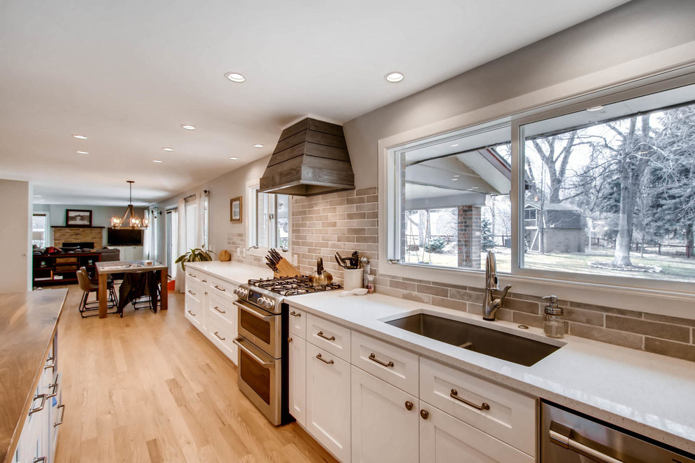 Example of a large transitional l-shaped light wood floor and yellow floor eat-in kitchen design in Other with an undermount sink, shaker cabinets, white cabinets, quartz countertops, multicolored backsplash, porcelain backsplash, stainless steel appliances, an island and white countertops