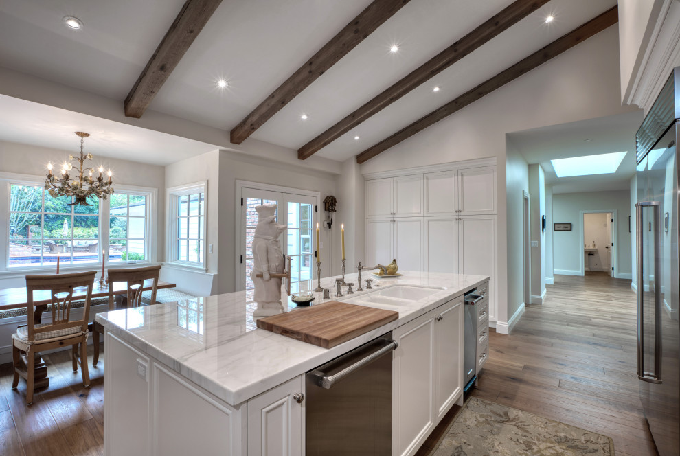 Large transitional u-shaped dark wood floor and beige floor eat-in kitchen photo in Los Angeles with a double-bowl sink, recessed-panel cabinets, white cabinets, marble countertops, beige backsplash, ceramic backsplash, stainless steel appliances, an island and white countertops