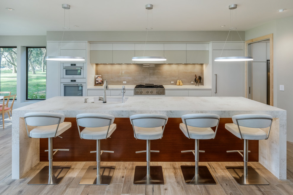 Design ideas for a large contemporary galley kitchen/diner in Sacramento with a submerged sink, flat-panel cabinets, white cabinets, composite countertops, beige splashback, engineered quartz splashback, white appliances, porcelain flooring, an island, beige floors and white worktops.