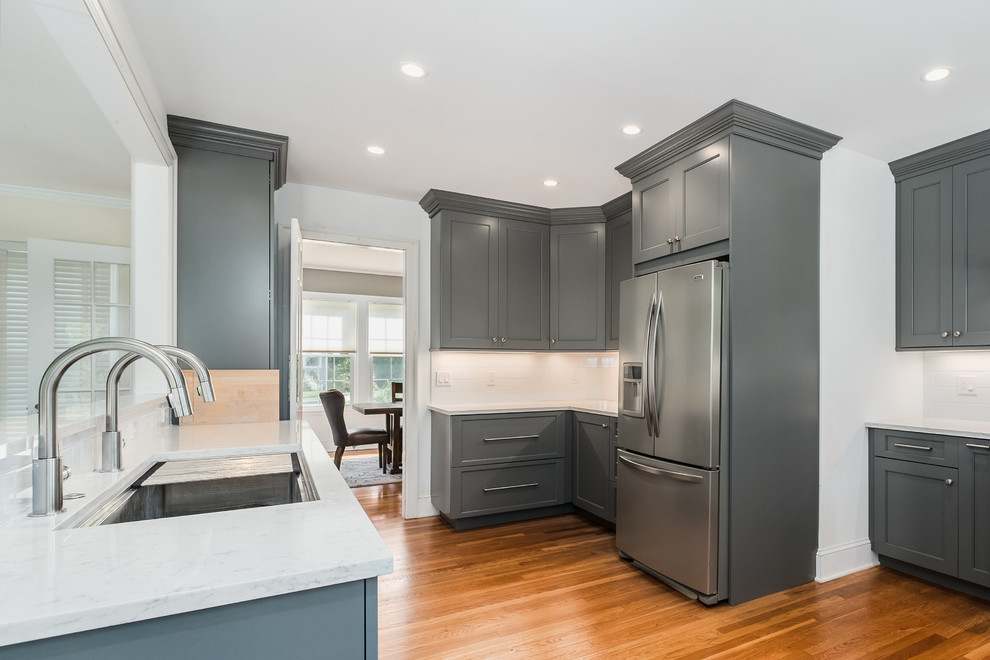 Large transitional l-shaped medium tone wood floor kitchen pantry photo in Bridgeport with a double-bowl sink, flat-panel cabinets, gray cabinets, quartz countertops, white backsplash, ceramic backsplash and stainless steel appliances