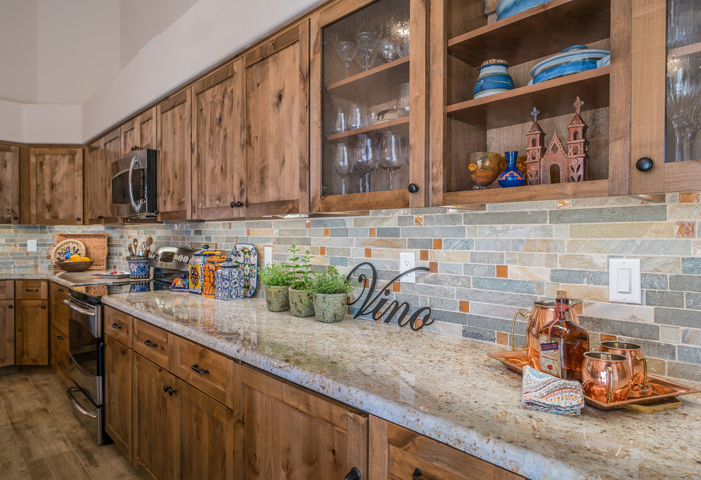 Example of a mid-sized mountain style l-shaped porcelain tile and beige floor eat-in kitchen design in Minneapolis with shaker cabinets, medium tone wood cabinets, granite countertops, green backsplash, stone tile backsplash, stainless steel appliances, an island and a farmhouse sink