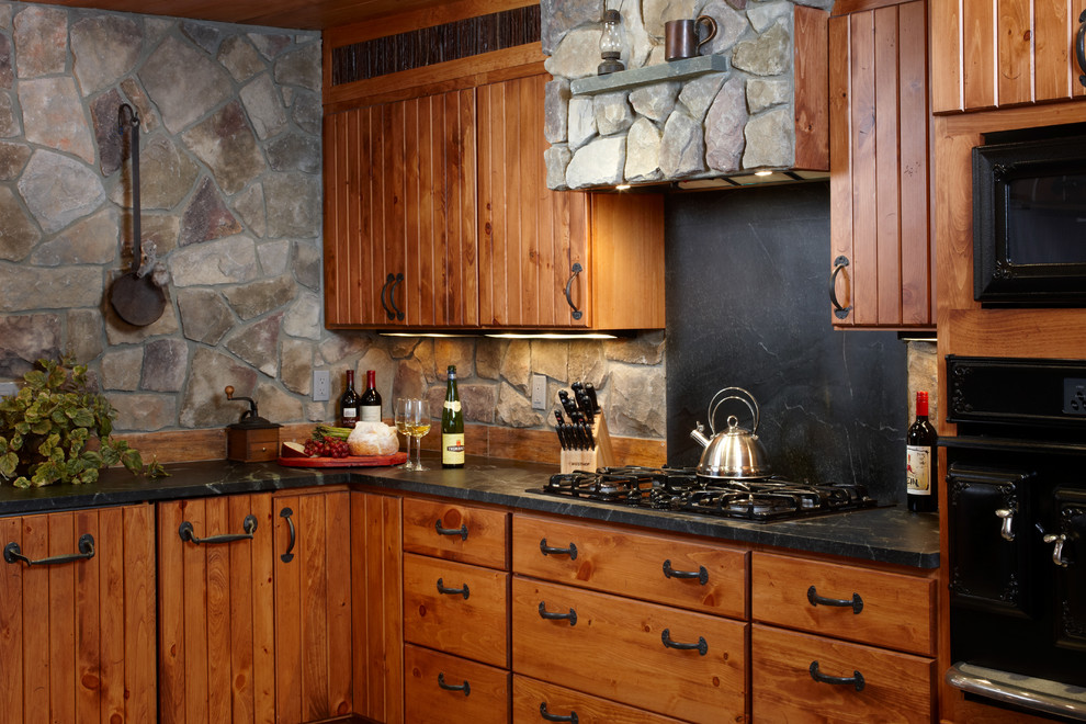 Inspiration för rustika kök, med en rustik diskho, skåp i mellenmörkt trä, bänkskiva i täljsten, stänkskydd i stenkakel, svarta vitvaror och mellanmörkt trägolv