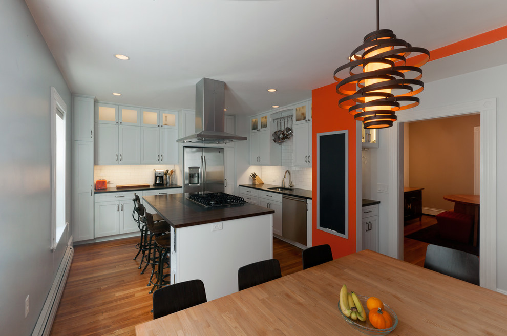 Imagen de cocina comedor contemporánea con armarios estilo shaker, salpicadero de azulejos tipo metro, electrodomésticos de acero inoxidable, encimera de madera y salpicadero blanco