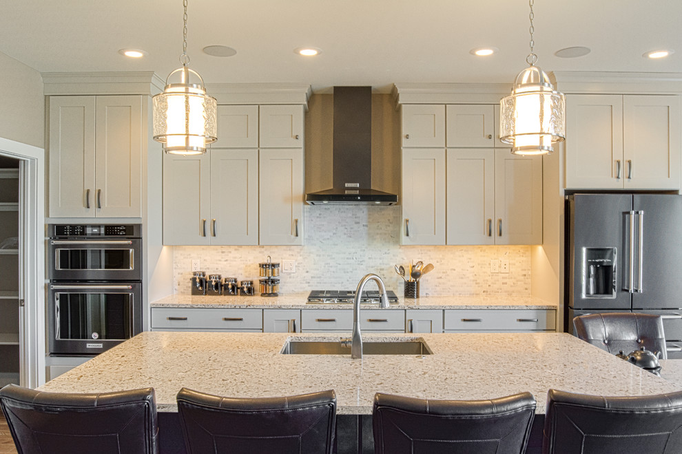Foto på ett mellanstort funkis linjärt kök och matrum, med en enkel diskho, vita skåp, bänkskiva i kvarts, grått stänkskydd, rostfria vitvaror, mellanmörkt trägolv, en köksö och brunt golv