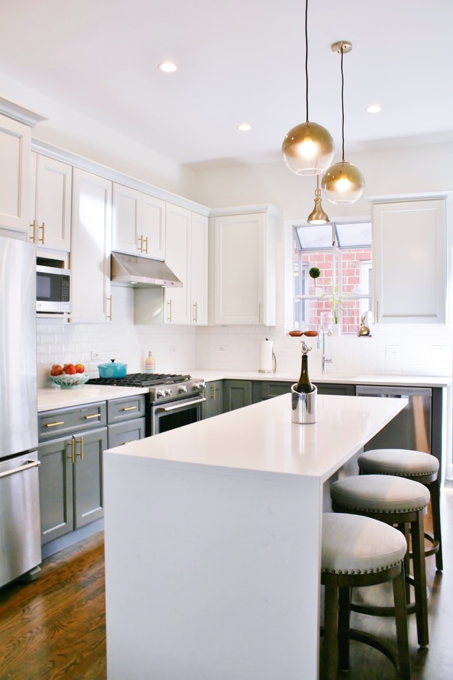 Inspiration for a mid-sized transitional l-shaped medium tone wood floor and brown floor open concept kitchen remodel in Chicago with an undermount sink, shaker cabinets, gray cabinets, quartz countertops, white backsplash, subway tile backsplash, stainless steel appliances and an island