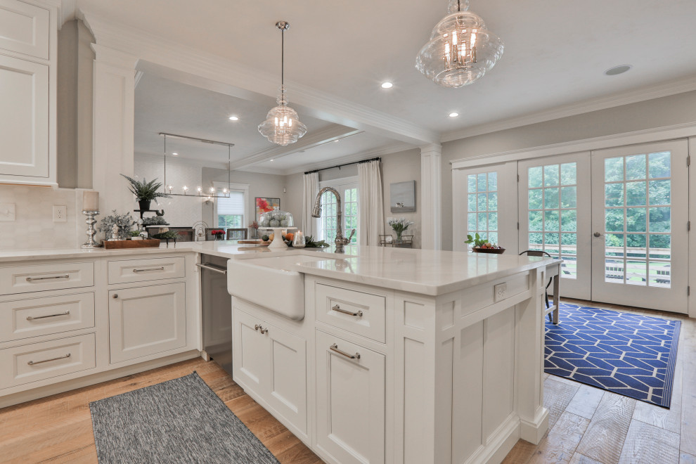 Foto på ett stort vintage vit kök, med en rustik diskho, luckor med profilerade fronter, vita skåp, bänkskiva i kvarts, vitt stänkskydd, stänkskydd i marmor, rostfria vitvaror, ljust trägolv, en köksö och flerfärgat golv