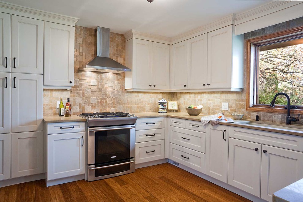 Exempel på ett avskilt, mellanstort klassiskt beige beige u-kök, med en undermonterad diskho, luckor med infälld panel, vita skåp, bänkskiva i kvarts, brunt stänkskydd, stänkskydd i travertin, rostfria vitvaror, mörkt trägolv, en halv köksö och brunt golv