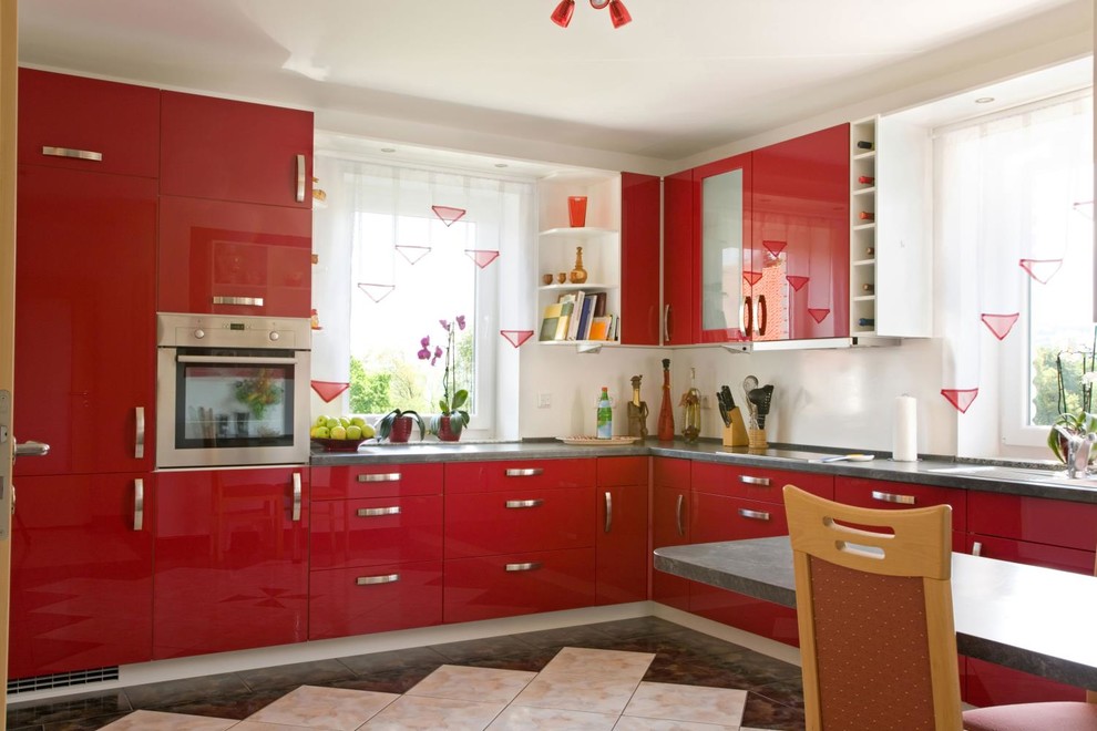 Foto di una cucina minimalista di medie dimensioni con lavello da incasso, ante di vetro, ante rosse, top in cemento, pavimento multicolore e top grigio
