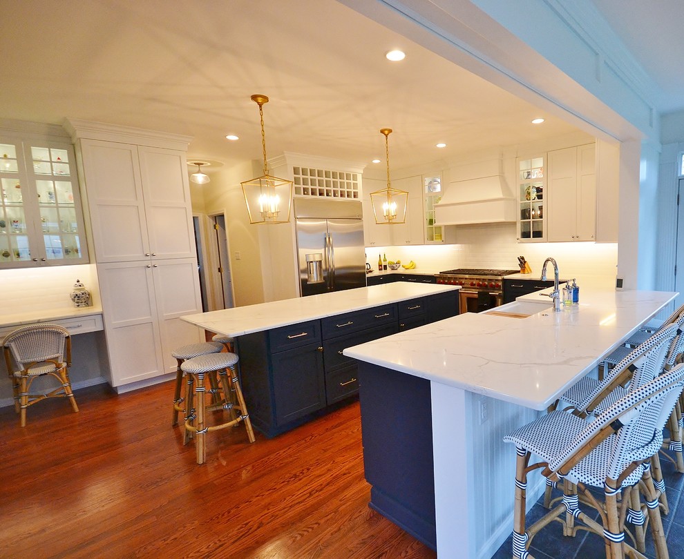 Inspiration for a large transitional l-shaped medium tone wood floor and brown floor eat-in kitchen remodel in Philadelphia with a farmhouse sink, flat-panel cabinets, blue cabinets, granite countertops, white backsplash, subway tile backsplash, stainless steel appliances, an island and white countertops