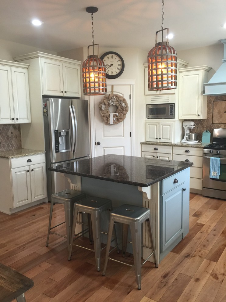 Kitchen - mid-sized transitional l-shaped medium tone wood floor and brown floor kitchen idea in Austin with raised-panel cabinets, white cabinets, granite countertops, brown backsplash, ceramic backsplash, stainless steel appliances and an island