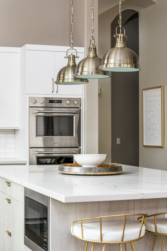 Exempel på ett modernt vit vitt kök, med en enkel diskho, släta luckor, vita skåp, marmorbänkskiva, vitt stänkskydd, stänkskydd i keramik, rostfria vitvaror, laminatgolv, en köksö och brunt golv