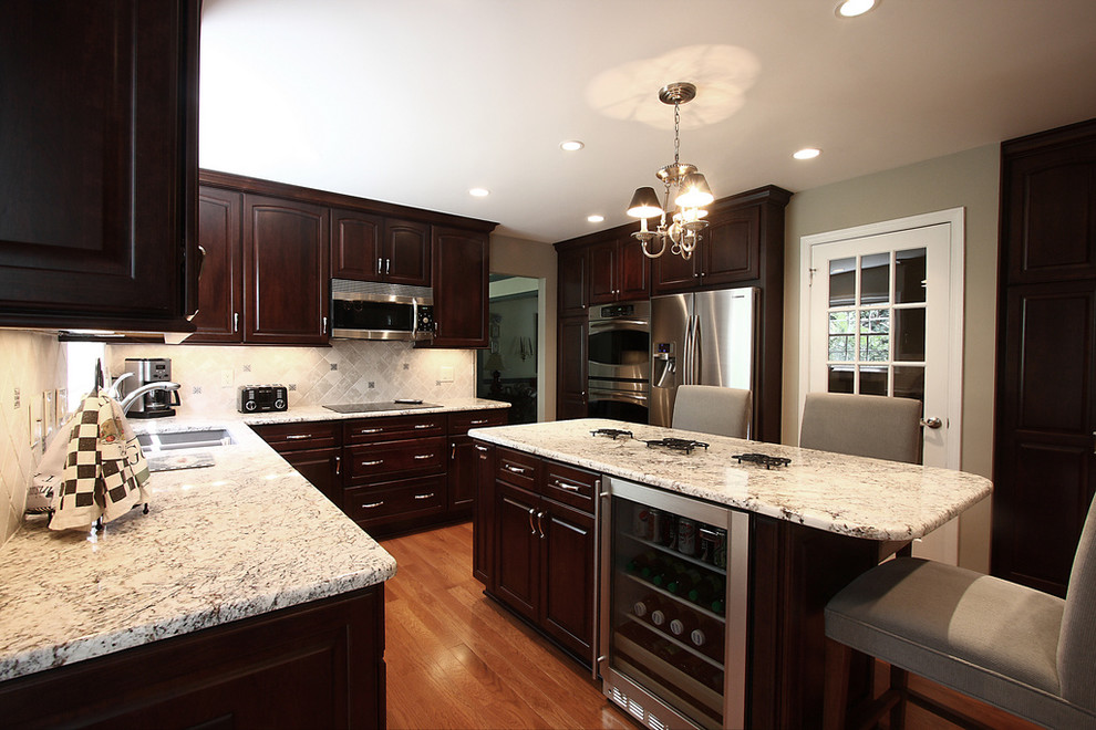 Foto de cocina actual con armarios con paneles con relieve, electrodomésticos de acero inoxidable, encimera de granito y barras de cocina