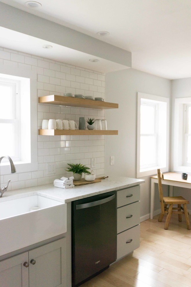 Idéer för att renovera ett litet lantligt vit vitt kök, med en rustik diskho, skåp i shakerstil, grå skåp, bänkskiva i kvarts, vitt stänkskydd, stänkskydd i tunnelbanekakel, rostfria vitvaror, ljust trägolv och brunt golv