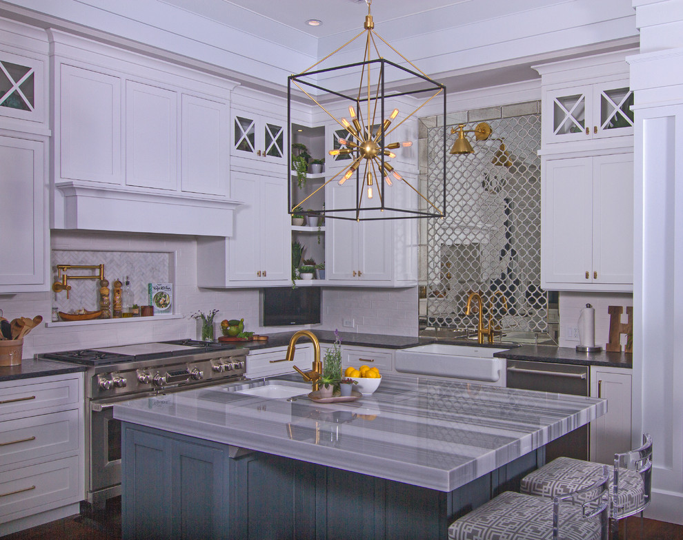 Photo of a medium sized midcentury open plan kitchen in Tampa with a belfast sink, shaker cabinets, white cabinets, marble worktops, white splashback, metro tiled splashback, stainless steel appliances, medium hardwood flooring, an island, brown floors and multicoloured worktops.