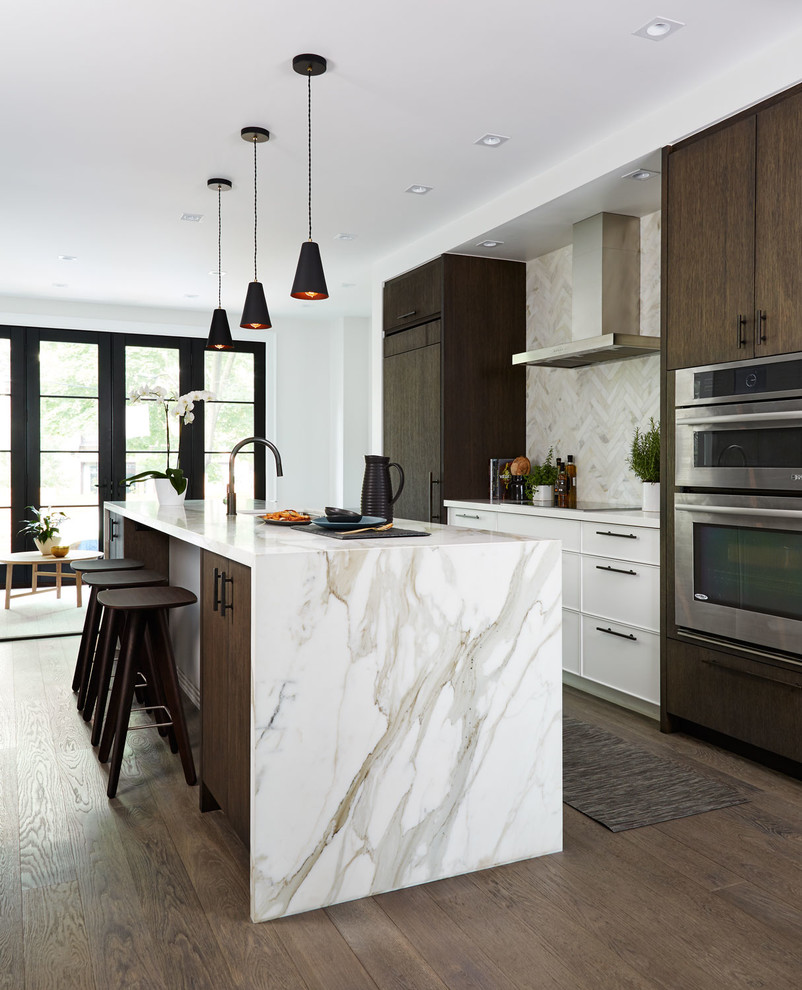 Idéer för att renovera ett mellanstort funkis beige beige kök med öppen planlösning, med en undermonterad diskho, släta luckor, marmorbänkskiva, stänkskydd i marmor, en köksö, mörkt trägolv, brunt golv, integrerade vitvaror och beige stänkskydd