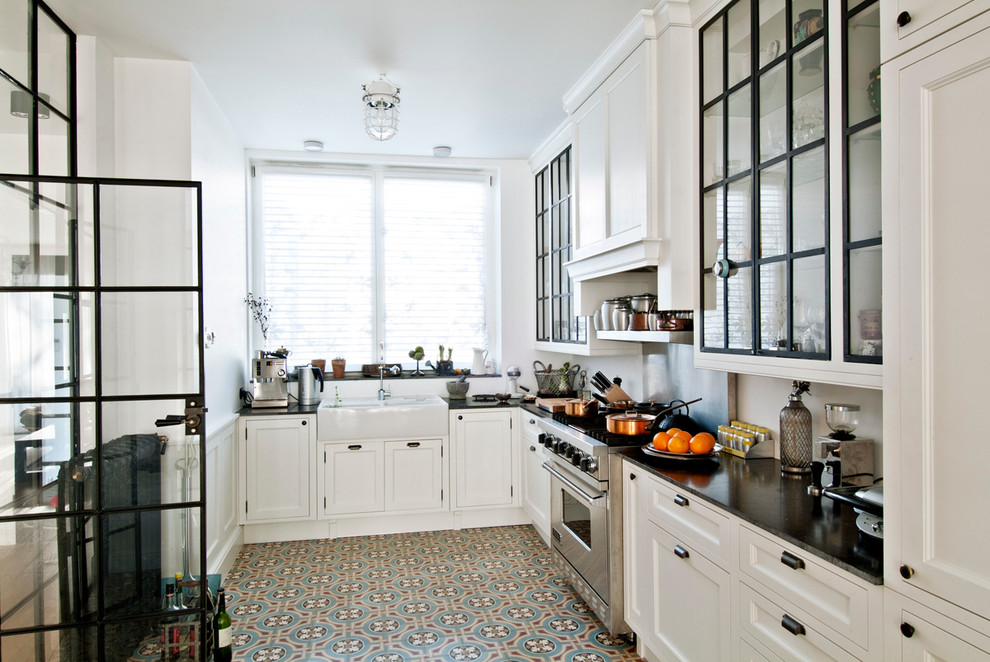Geschlossene Moderne Küche in L-Form mit Landhausspüle, Glasfronten, weißen Schränken, Küchengeräten aus Edelstahl und Speckstein-Arbeitsplatte in Los Angeles