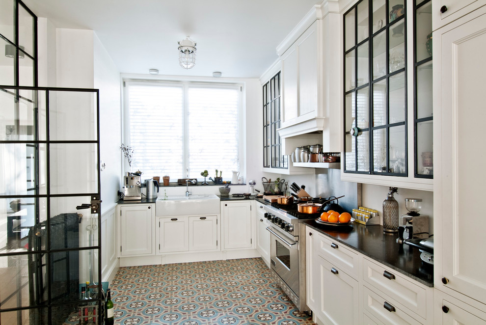 Design ideas for a contemporary l-shaped enclosed kitchen in Los Angeles with a belfast sink, glass-front cabinets, white cabinets, stainless steel appliances and soapstone worktops.