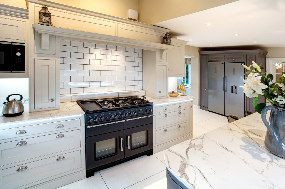 Bild på ett stort funkis vit vitt kök och matrum, med skåp i shakerstil, grå skåp, bänkskiva i kvartsit, vitt stänkskydd, stänkskydd i tunnelbanekakel, vinylgolv, en köksö och vitt golv