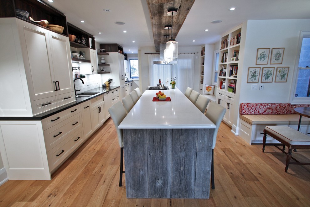 Eat-in kitchen - large traditional galley light wood floor eat-in kitchen idea in Toronto with an undermount sink, beaded inset cabinets, white cabinets, quartz countertops, white backsplash, subway tile backsplash, stainless steel appliances and an island