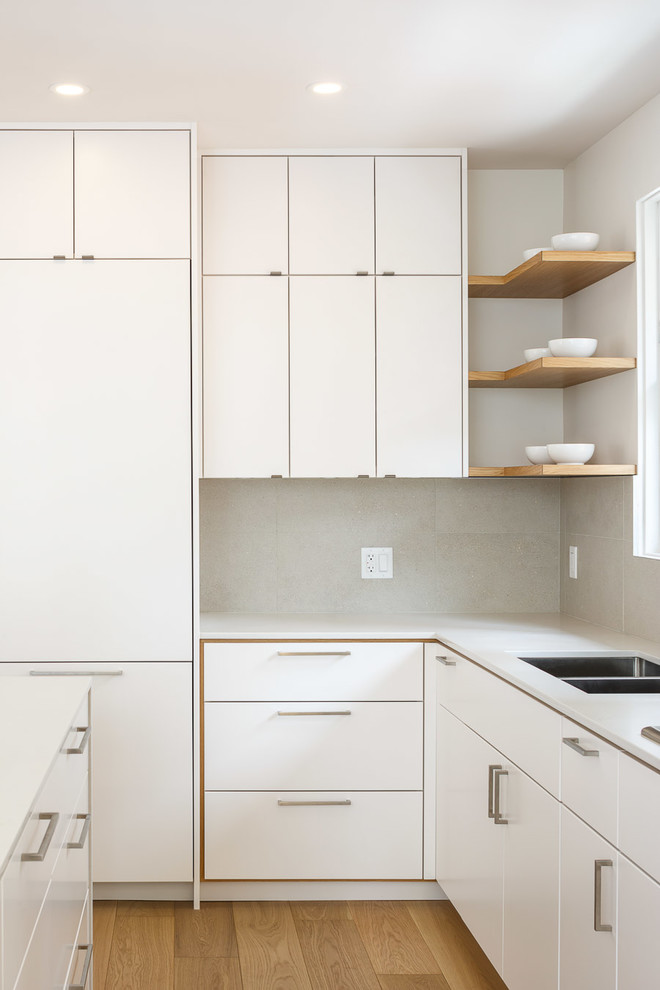 Idéer för ett mellanstort modernt kök, med en undermonterad diskho, släta luckor, vita skåp, bänkskiva i koppar, rostfria vitvaror, ljust trägolv, en köksö och beiget golv