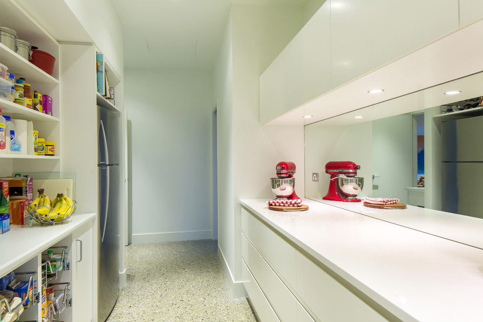 Bild på ett funkis kök, med släta luckor, vita skåp, träbänkskiva, stänkskydd med metallisk yta, spegel som stänkskydd, rostfria vitvaror och en halv köksö