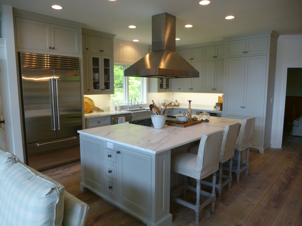 Inredning av ett klassiskt mellanstort kök, med en undermonterad diskho, skåp i shakerstil, gröna skåp, marmorbänkskiva, rostfria vitvaror, ljust trägolv och en köksö