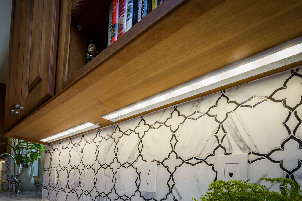 Inredning av ett medelhavsstil mellanstort u-kök, med en rustik diskho, luckor med upphöjd panel, bruna skåp, marmorbänkskiva, vitt stänkskydd, stänkskydd i stenkakel, rostfria vitvaror, travertin golv och en köksö