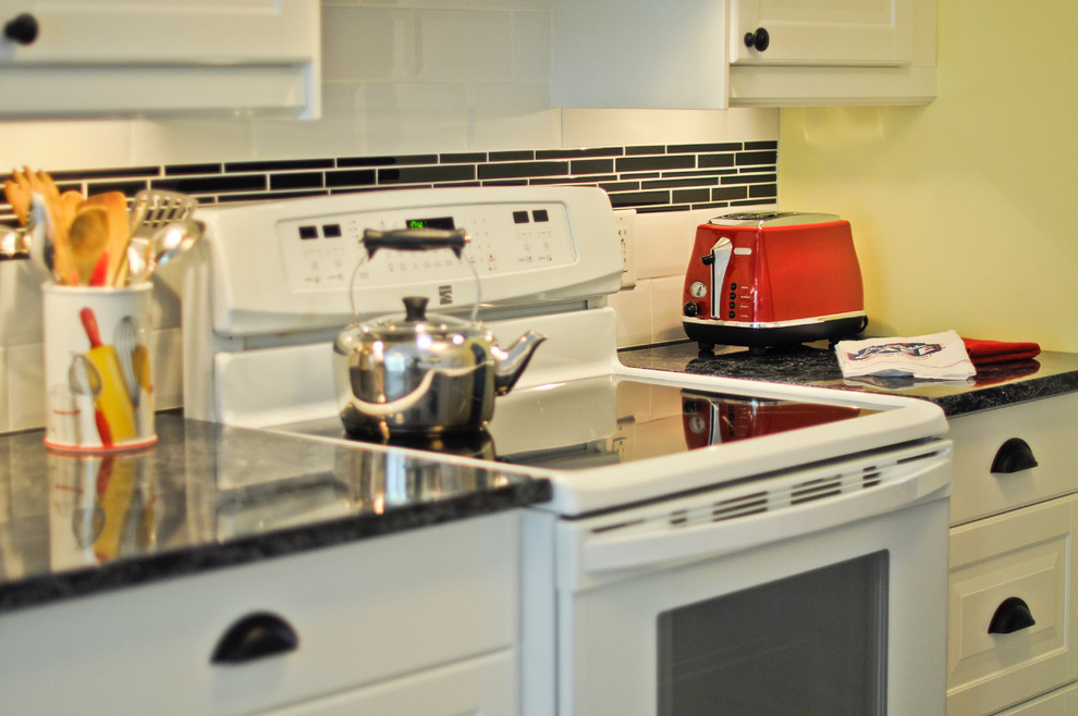 Zweizeilige Klassische Küche ohne Insel mit Waschbecken, profilierten Schrankfronten, weißen Schränken, Küchenrückwand in Schwarz, weißen Elektrogeräten und Korkboden in Ottawa