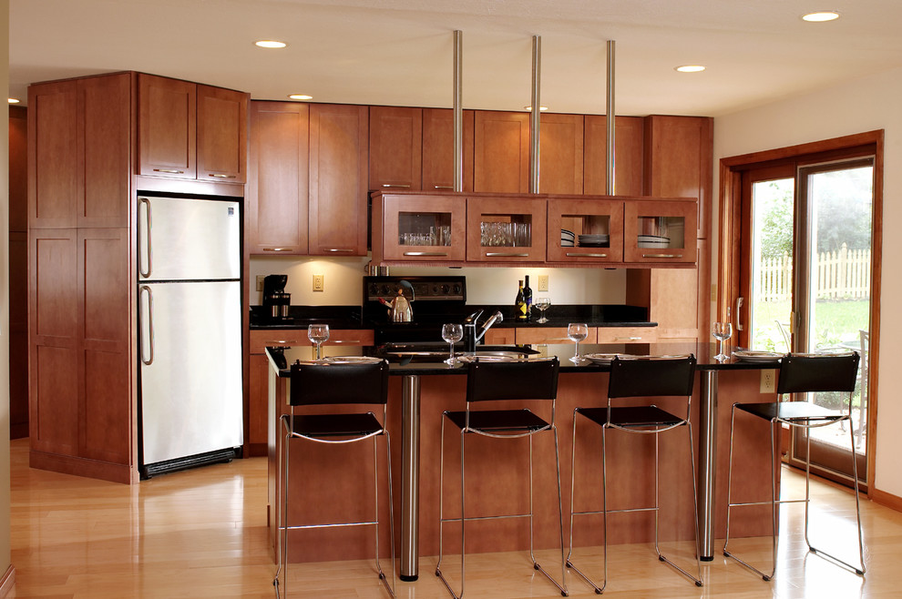 Foto på ett stort funkis linjärt kök med öppen planlösning, med en dubbel diskho, skåp i shakerstil, skåp i mellenmörkt trä, granitbänkskiva, svarta vitvaror, ljust trägolv och en köksö