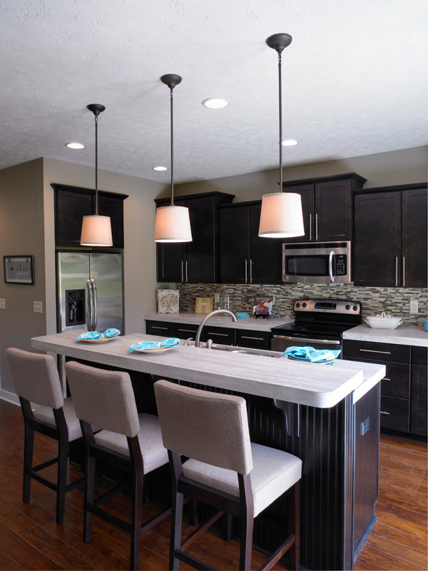 Example of a mid-sized transitional l-shaped open concept kitchen design in Other with shaker cabinets, dark wood cabinets, laminate countertops, stainless steel appliances, an island and a drop-in sink