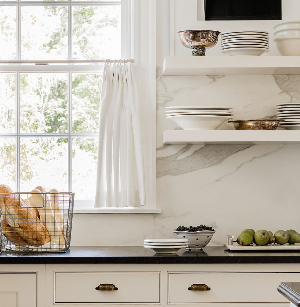 Kitchen - transitional light wood floor and gray floor kitchen idea with shaker cabinets, white cabinets, granite countertops, white backsplash, marble backsplash, stainless steel appliances, an island and black countertops