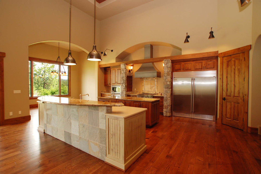Exemple d'une très grande cuisine ouverte parallèle montagne en bois brun avec un placard avec porte à panneau surélevé, un plan de travail en granite, une crédence beige, une crédence en carrelage de pierre et 2 îlots.